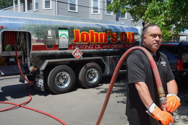heating oil tank delivery driver and truck pulling a hose