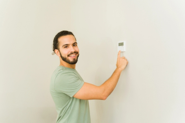homeowner adjusting home thermostat for the summer
