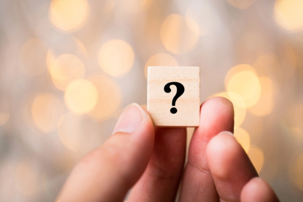 question mark on a wooden chip held by a woman depicting Hot and Cold Spots in House FAQs